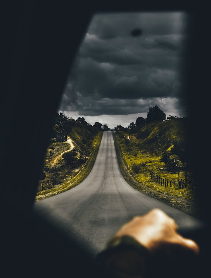 A moody drive on an open road with dark clouds overhead, capturing a sense of adventure and solitude.