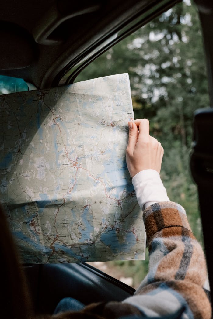 A person holding a map inside a car, ready for a journey.